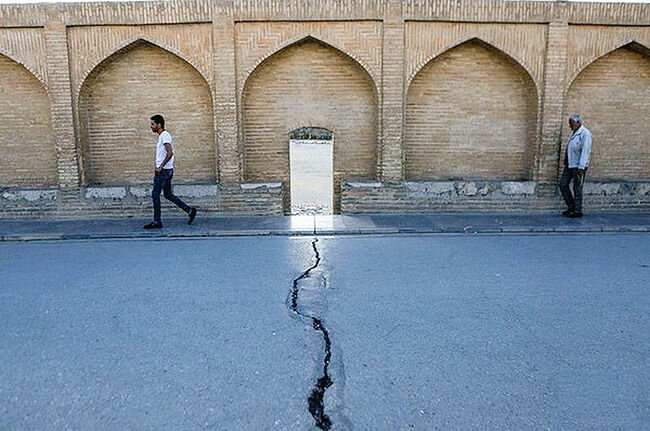 شکاف ناشی از فرونشست زمین در خیابانی کنار دیوار آجری تاریخی